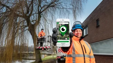 Photo of two public servants working in public space. Meanwhile holding out a phone with the Meld'R app showing on the screen.