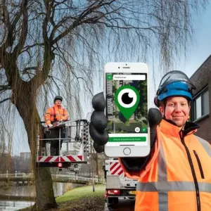 Photo of two public servants working in public space. Meanwhile holding out a phone with the Meld'R app showing on the screen.